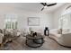 Bright living room featuring neutral furniture, a ceiling fan, and large windows with plantation shutters at 1625 W Gunstock Loop, Chandler, AZ 85286