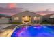 Backyard pool at dusk, lit up with colorful lights and a covered patio at 18630 W Lawrence Ln, Waddell, AZ 85355