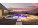 A backyard pool with raised spa, rock landscaping and travertine pathway provides an oasis for enjoying evenings at 18630 W Lawrence Ln, Waddell, AZ 85355