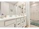 Bathroom with double sinks, white cabinets, and a shower/tub combo at 18630 W Lawrence Ln, Waddell, AZ 85355