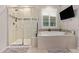 Bathroom with walk-in shower, bathtub and a window with plantation shutters at 18630 W Lawrence Ln, Waddell, AZ 85355
