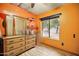 Bedroom featuring vibrant orange walls, wood flooring, and natural light from a window at 2320 W El Alba Way, Chandler, AZ 85224