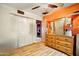 This bedroom has a wood floor, orange walls, and closet for the home's occupants at 2320 W El Alba Way, Chandler, AZ 85224