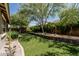 Beautifully landscaped backyard featuring artificial turf, mature trees, and a decorative stone retaining wall at 3349 E Merlot St, Gilbert, AZ 85298