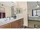 Bright bathroom features a vanity with a sink, mirror, and wood cabinets, and a view into the bedroom at 3510 E Hampton Ave # 74, Mesa, AZ 85204