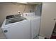 Laundry room with a white front-load washer and dryer, and an ironing board at 3510 E Hampton Ave # 74, Mesa, AZ 85204