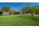 Backyard with mature trees, ranch-style home, and lush green grass for a serene and inviting outdoor space at 3738 E Hash Knife Draw Rd, Queen Creek, AZ 85140