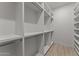 Bright walk-in closet with custom built-in shelving, closet rods, and wood-look tile flooring at 39302 N 30Th Dr, Phoenix, AZ 85086