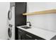 Modern laundry room featuring a stacked washer/dryer unit and sink with storage at 4002 N 33Rd Pl, Phoenix, AZ 85018