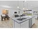 Bright, open kitchen with island sink and stainless steel dishwasher overlooking living spaces at 40990 W Agave Rd, Maricopa, AZ 85138