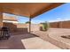 Cozy covered back patio area with a barbecue, gravel landscaping, and a brick fire pit area at 44859 W Sage Brush Dr, Maricopa, AZ 85139