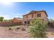 Large backyard featuring gravel landscaping, an in-ground firepit, green lawn area and a covered patio at 44859 W Sage Brush Dr, Maricopa, AZ 85139