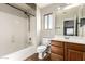 This bathroom features a shower-tub combo, tile flooring, and a wood vanity at 44859 W Sage Brush Dr, Maricopa, AZ 85139