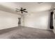 Spacious bedroom with ceiling fan, neutral walls, and carpet; access to additional room at 44859 W Sage Brush Dr, Maricopa, AZ 85139