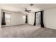 Bright, carpeted bedroom showcasing neutral walls, ceiling fan, and natural light at 44859 W Sage Brush Dr, Maricopa, AZ 85139