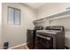 This laundry room features modern washer and dryer units, and shelving at 44859 W Sage Brush Dr, Maricopa, AZ 85139