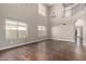 Bright living room featuring beautiful hardwood floors, large windows, and a soaring two-story ceiling at 44859 W Sage Brush Dr, Maricopa, AZ 85139