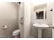 This powder room features a pedestal sink, toilet, and a framed mirror at 44859 W Sage Brush Dr, Maricopa, AZ 85139