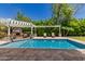 Private backyard pool area with covered lounge area, fireplace, mature landscaping, and comfortable lounge chairs at 6235 S Odessa Dr, Gilbert, AZ 85298