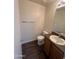 Cozy half bathroom with wood-look floors, single sink vanity, toilet, and towel bar near entry door at 6339 W Sophie Ln, Laveen, AZ 85339