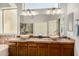 Bathroom with double sinks, large mirror, and wood cabinets at 6808 W Angela Dr, Glendale, AZ 85308