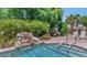 Inviting pool area with a rock waterfall feature, lush foliage, and poolside seating at 8210 W Wethersfield Rd, Peoria, AZ 85381