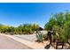 View of the home and driveway from the street, highlighting lush desert landscaping and an address marker at 8555 E Tecolote Cir, Scottsdale, AZ 85266