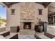 Close up of an outdoor fireplace with stone facade and seating area on a covered patio at 8555 E Tecolote Cir, Scottsdale, AZ 85266