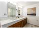 Bathroom featuring dual sinks, wood cabinetry, modern fixtures, and neutral tiling at 9502 N 47Th St, Phoenix, AZ 85028