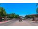 View of community entrance gate with brick pillars, mature landscaping, and a view of the residential buildings beyond at 1367 S Country Club Dr # 1167, Mesa, AZ 85210