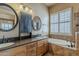 Bathroom featuring dual sinks, custom lighting, a soaking tub, and a window for natural light and ventilation at 1391 W Windhaven Ave, Gilbert, AZ 85233