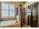 Luxurious bathroom with a soaking tub, glass-enclosed shower, and a window for natural light and ventilation at 1391 W Windhaven Ave, Gilbert, AZ 85233