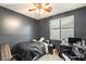 Cozy bedroom with a ceiling fan, large window, and black furniture at 14752 W Evans Dr, Surprise, AZ 85379