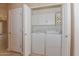 A bi-fold door opens to a laundry area with a washer and dryer and upper cabinets at 15806 N 107Th Pl, Scottsdale, AZ 85255