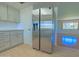 Kitchen with stainless steel fridge, white cabinets, light countertops, and tile backsplash, with view to living room at 1726 W Claremont St, Phoenix, AZ 85015