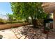 Backyard featuring an outdoor patio with charming stone tiling, a leafy fruit tree, and lush greenery at 21614 N 59Th Ln, Glendale, AZ 85308