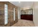 Well-lit bathroom showcasing dual sinks, dark wood cabinetry, and tiled walls at 21614 N 59Th Ln, Glendale, AZ 85308