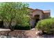 Attractive home showcasing a welcoming entrance, complemented by mature trees and beautifully landscaped surroundings at 21614 N 59Th Ln, Glendale, AZ 85308