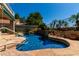 Backyard pool features a rock waterfall, tropical foliage, and a stone tile surround at 21614 N 59Th Ln, Glendale, AZ 85308