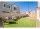 View of a green backyard with outdoor chairs, brick perimeter, and a privacy wall for peaceful relaxation at 2195 N Peden Dr, Chandler, AZ 85225
