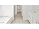 Bright bathroom featuring tile floors, a soaking tub, white vanity, and walk-in closet at 24486 W Grenadine Rd, Buckeye, AZ 85326