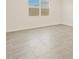 Bright and airy bedroom features neutral paint, tile flooring and a large window at 24486 W Grenadine Rd, Buckeye, AZ 85326