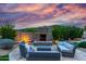 Backyard living space with stone fireplace, lush landscaping, and comfortable seating area at 2731 W Desert Ranch Rd, Phoenix, AZ 85086