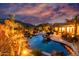 Backyard features a custom pool, rock waterfall, and lush desert landscaping with mountain views at sunset at 2731 W Desert Ranch Rd, Phoenix, AZ 85086