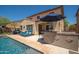 Covered outdoor kitchen with a built-in BBQ and counter seating overlooking a refreshing swimming pool and lounge area at 31046 N 138Th Ave, Peoria, AZ 85383