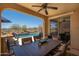 Covered outdoor patio featuring a dining table with chairs, a ceiling fan, and views of the backyard pool at 31046 N 138Th Ave, Peoria, AZ 85383