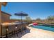 Outdoor kitchen featuring a built-in bar and seating area, overlooking a sparkling backyard swimming pool at 31046 N 138Th Ave, Peoria, AZ 85383