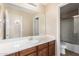 Bathroom featuring a wood vanity, sink, large mirror, and walk-in shower at 42160 W Arvada Ct, Maricopa, AZ 85138