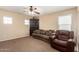 Comfortable living room with a ceiling fan, large sofa, and dark wood display cabinet at 42160 W Arvada Ct, Maricopa, AZ 85138