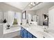 A light and bright main bathroom with a tub, shower and dual sink vanity with blue cabinets at 5133 E Juana Ct, Cave Creek, AZ 85331
